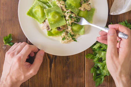Delicious green dumplings with spinach dough stuffed with cheese with champignon sauce. Italian Cuisine. On a wooden backgroundの写真素材