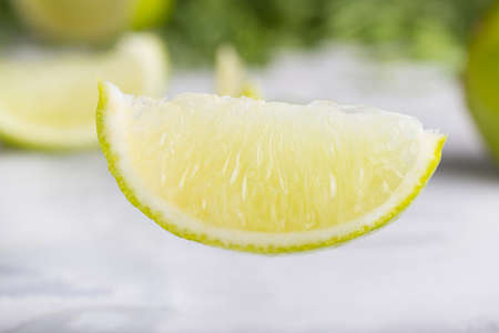 Slice of lime macro on white background with greens in the background. Citrus slice on a white background.の写真素材