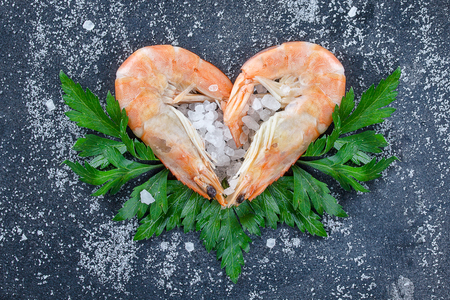 Raw prawns, shrimps with hearts with condiments on a stone background, strewn with sea salt and herbs. The shrimps lie in the form of a heart. Sea salt and shrimp.の写真素材