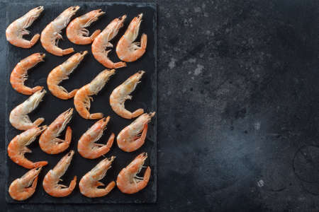 Good selection of raw shrimps for dinner on stone plate. Food background. A frame for your text. A...