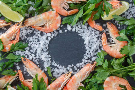 Shrimps with lime, herbs and sea salt on a black background. Frame for your text. Shrimp in parsley.の写真素材