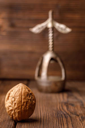 A walnut in a shell on a wooden background together with an old nutcracker. Walnut and beautiful...