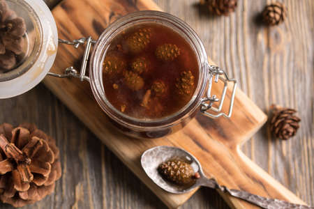 A jar of homemade jam made of pine cones on a dark wooden background. Monochrome.の写真素材