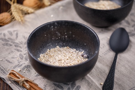 Levitating in a bowl of dry cereal oatmeal. Still-life on a wooden background. Textiles, nuts and cinnamon sticks.の写真素材