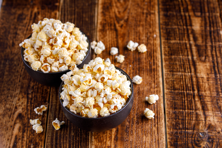 Two exquisite ceramic bowls with fresh popcorn. Still-life on a wooden background.の写真素材