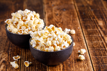 Two exquisite ceramic bowls with fresh popcorn. Still-life on a wooden background.の写真素材