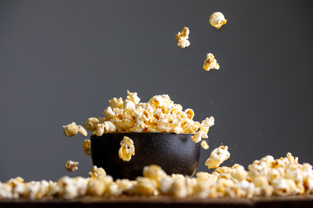 Levitating falling popcorn in a ceramic bowl and around it. Side view.の写真素材