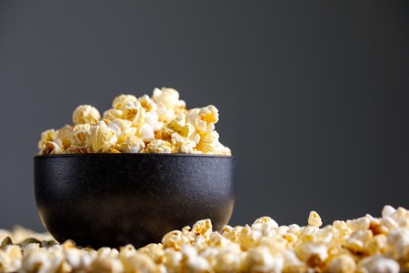 Popcorn in a black ceramic cup and around it. Side view.の写真素材