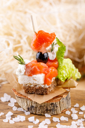 Canape with lightly salted salmon on a cut wood. Rustic. Close-up.の写真素材