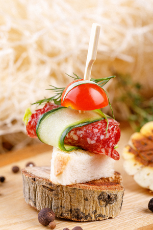 Canape with salami and vegetables on a wooden cut. Rustic. Close-up.の写真素材