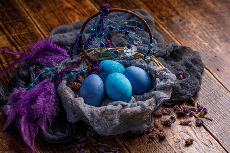 Unusually painted in dark blue and blue colors, Easter eggs decorated with feathers from the catcher dreams. Easter still life.の写真素材