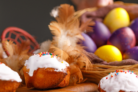 Cupcakes and dyed Easter eggs decorated with an attribute of a dream catcher. Still-life on a wooden...