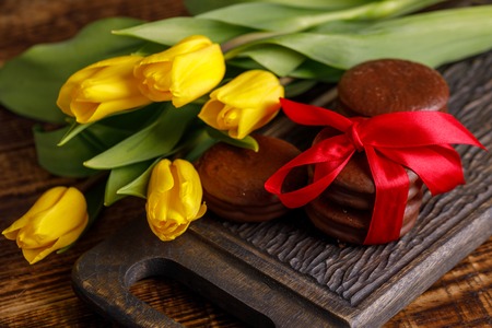A gift for Valentine's Day. Romantic treat. Chocolate biscuits with a delicate filling and a tulip flower.の写真素材