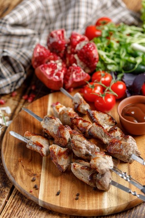 Shish kebabs on skewers close-up. Juicy appetizing meat cooked on an open fire. Rustic. Still life with textiles on a wooden background.の写真素材