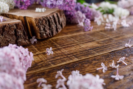 Wooden slept surrounded by lilac flowers of different shades. Still-life on a wooden background.の写真素材
