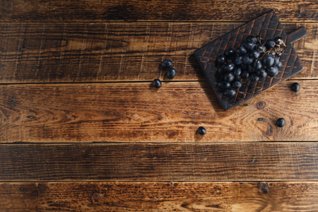 Dark grapes on a decorative board on a wooden background. Top view with space for text.の写真素材