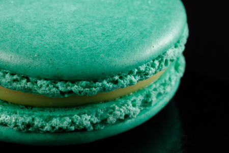 Bright juicy delicious macarons mint color on a black background. Close-up.の写真素材