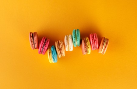 Colorful french macaroons on a yellow background. Dessert with tea or coffee. Top view.の写真素材