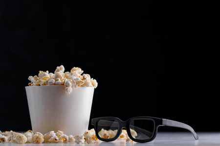 A bucket of popcorn and 3 d glasses on a dark background. Oscar Film Academy Concept. Snack for watching movies.の写真素材