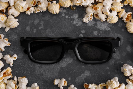 Glasses to watch a movie in a frame of popcorn. Cinema concept.
