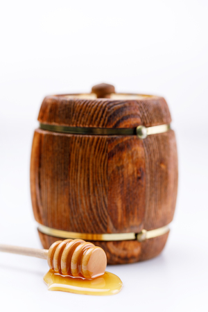 A barrel of honey and a spoon with a drop of tasty liquid on a white background. Isolated.の写真素材