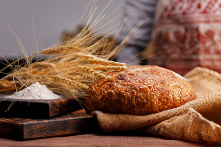 Craft bread on a wooden board and spikelets close-up. The concept of healthy food and traditional bakery. Rustic.の写真素材