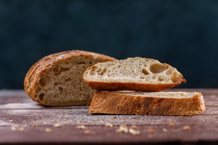 Sliced craft rye bread on a board close-up on a dark background. The concept of healthy food and...