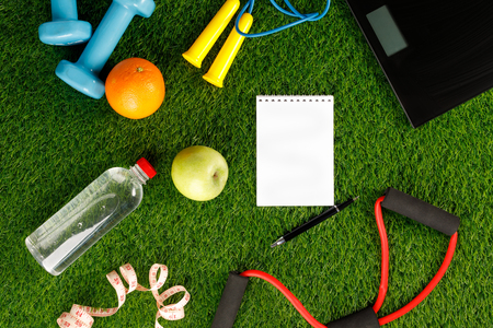 Set for sports with equipment, and a bottle of water and an apple on a background of green grass. Flat lay. Place under the text. Copy space.の写真素材