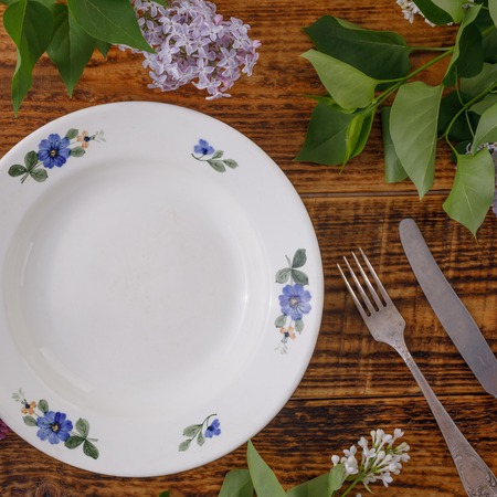 Plate and decor of flowers on the background of vintage wooden planks.Vintage background with lilac...