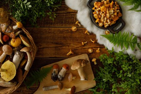 Mushrooms on old wooden background. Card on autumn or summertime. Forest harvest. Boletus, chanterelles, leaves, berries. Top view. Flat layの写真素材