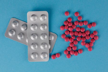 Packing pills. A scattering of red pills on a blue background. Close-up.の写真素材