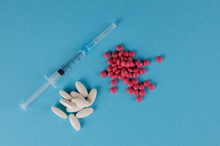 Packing pills and medical syringe. A scattering of pills on a blue background. Close-up.の写真素材