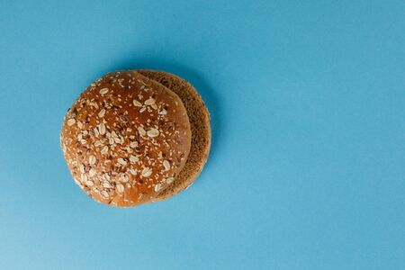 Rye bun empty isolated. American food classic rye round burger bread isolated on a blue background. Grilled burger bun top. Close-up.の写真素材