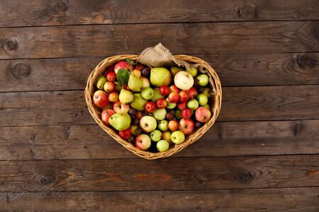 Basket full of ripe apples and pears on a wooden background. View from above. Flat lay. Copy space. Harvest concept. A basket full of fruit.の写真素材