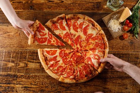 Pizza Margarita on a wooden table. Still life with hands and ingredients. Top view.の写真素材
