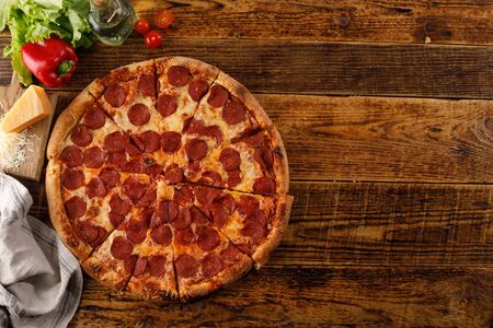 Pepperoni pizza on a wooden table. Still life with ingredients. Top view.の写真素材