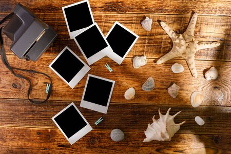 Top view of blank photographs next to a camera on a wooden table. The concept of pleasant memories.