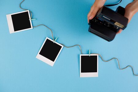 Instant photo frames and camera on a blue background. Concept of preservation of memories. Flat lay. Copy space.の写真素材