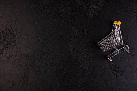 Shopaholic. Buyer. Shopping concept. Close-up. From above. Isolated shopping trolley on a black...