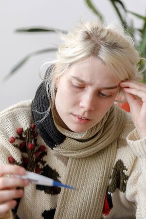 The girl in the sweater is sick sitting on the couch. Colds and flu. The patient caught a cold,...