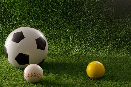 Soccer and baseball balls on a green field. The concept of football matches. Copy space. Close-up.
