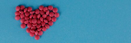 A scattering of red pills in the form of a heart on a blue background. Close-up.の写真素材
