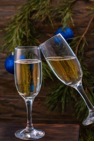 Glasses of champagne with bubbles on the background of Christmas decorations. Glasses touch during a festive toast. Beautiful card. Macroの写真素材
