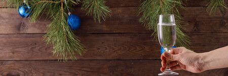 Glass of champagne in hand with bubbles on the background of Christmas decorations. Beautiful greeting card.の写真素材