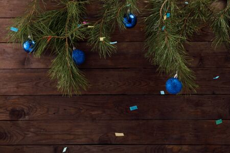 Christmas tree branches on a wooden background. A decoration of Christmas balls in a trendy classic...
