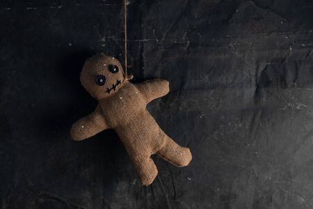 Voodoo doll on a black background with dramatic lighting. The concept of witchcraft and black art and the occult. Burlap doll. Copy space.の写真素材
