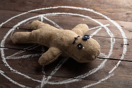 Voodoo doll on a wooden background with dramatic lighting. The concept of witchcraft and black art...