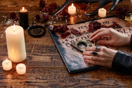 Mystic ritual with Devil's board and candles. The girl calls spirits.The mystical atmosphere of occultism and black magic. Witch.の写真素材