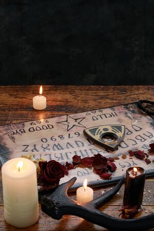 Mystic ritual with Ouija and candles. Devil's board concept, black magic or fortune telling rite with occult and esoteric symbols. Occultism.の写真素材