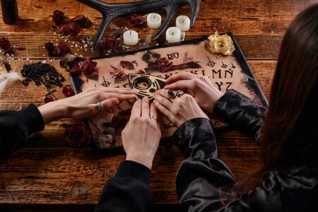 People conducting a seance using a Board, or Talking Spirit Board, with white candles. Shot from overhead.の写真素材